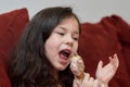 expressive young girl is eating chicken and vegetables for dinner on the couch while watching cartoons Royalty Free Stock Photo