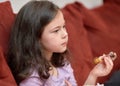 expressive young girl is eating chicken and vegetables for dinner on the couch while watching cartoons Royalty Free Stock Photo