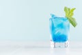 Exquisite blue cocktail for celebration in beach style with blue curacao, ice cube, green mint in mint color bar interior on white