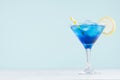 Exquisite blue cocktail for celebration in beach style with blue curacao, ice cube, lemon slice, yellow straw in mint color bar.