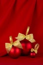 Exquisite christmas background - red balls with golden ribbon on deep red silk curtain with smooth waves, closeup, vertical. New.