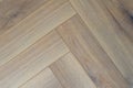 Exquisite herringbone parquet texture in warm gray tones, creating coziness and elegance in the interior Royalty Free Stock Photo