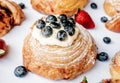 Exquisite lemon pie croissant dough role with blackberries on top on a white table and flavored roles around it