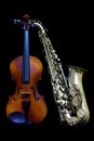 Vintage violin and silver matte finished alto saxophone on black background