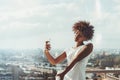 Black girl taking selfie on balcony of high-rise