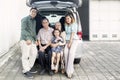 Asian family sitting on the car trunk