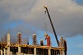 An extended boom of a truck crane lifts a concrete tank to the top floor of a building under construction.