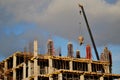 An extended boom of a truck crane lifts a concrete tank to the top floor of a building under construction.