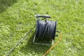 Extension cord, electric cable on a reel on the grass for connecting garden tools, lawn mowers Royalty Free Stock Photo