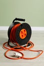 Extension cord reel on floor near light green wall. Electrician\'s equipment Royalty Free Stock Photo