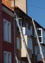 An extension ladder leans against the front of a multifamily housing building in preparation of roof repairs Royalty Free Stock Photo