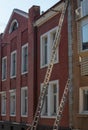 An extension ladder leans against the front of a multifamily housing building in preparation of roof repairs Royalty Free Stock Photo