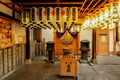 Extensive interior of Japanese shrine with decorate paper lanterns, donation box and iron incense pot