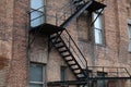 Exterior black fire escape staircase attached to the side of a red brick building Royalty Free Stock Photo