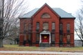 Exterior of boarded up and abandoned brick asylum hospital building with broken windows