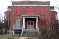 Exterior of boarded up and abandoned brick asylum hospital building with broken windows