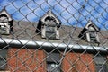 Exterior of boarded up and abandoned brick asylum hospital building with broken windows surrounded by chain link fence Royalty Free Stock Photo