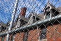 Exterior of boarded up and abandoned brick asylum hospital building with broken windows surrounded by chain link fence Royalty Free Stock Photo