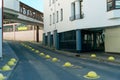 Exterior of the building with columns and large panoramic windows. The road leading to a multi-level parking lot. Unusual modern