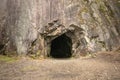 Rock wall with a dark hole, entrance to the cave in Spro, Mineral historic mine. Nesodden Norway. Nesoddtangen peninsula. Royalty Free Stock Photo