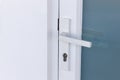 Exterior door handle and Security lock on Metal frame. Aluminum door knob. Modern white  door with metal door handle over the whit Royalty Free Stock Photo