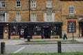 Exterior The Edinburgh Woolen Mill shop in Broadway, Cotswolds, UK, couple walking past