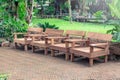 Wooden chairs place on brick floor surrounded with green nature. Royalty Free Stock Photo