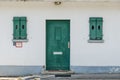 old rough green wooden door and windows on white concrete wall. Royalty Free Stock Photo