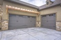 Exterior of a home with view of gray double garage doors and stone wall