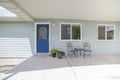 Exterior of a house with blue front door and two potted flowers at the doorstep