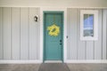 Exterior of a house with gray walls and blue green door with yellow flower wreath Royalty Free Stock Photo