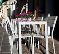 Exterior of an italian bar on the street with white chairs and tables. In every table there is a cyclamen pot Royalty Free Stock Photo