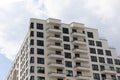 Exterior look of high modern new-built apartment house with beige facade, windows and balcony. Ground view at sky Royalty Free Stock Photo