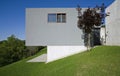 Exterior of a modern colored concrete house. A cube in the middle of the green. Profile view