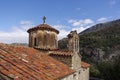 Greek Orthodox Monastery with cross above dome, against blue sky with clouds.