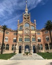 Exterior picture about a historic, old spanish cathedral, with green gress and palm trees, and a bit cloudy blue sky in background