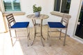 Exterior Rear Patio With High Table And Two Chairs With Blue Cushions