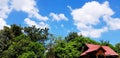 Exterior red roof of house with green tree, blue sky and white clouds with copy space Royalty Free Stock Photo