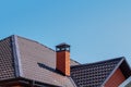 Brick chimney pipe on metal roof of a private house against the sky Royalty Free Stock Photo