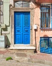 Blue painted decorated metal door and wrought iron window in a stone wall painted in orange and green on city street Royalty Free Stock Photo