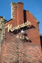 Exterior shot of a red brick building with metal brackted Newcastle Ales advertisement sign