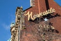 Exterior shot of a red brick building with metal brackted Newcastle Ales advertisement sign
