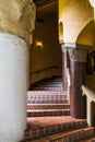 An exterior stairway in an old Spanish style building curves through columns Royalty Free Stock Photo