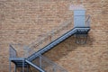 Exterior steel staircase leading to a closed door on a red brick building wall Royalty Free Stock Photo