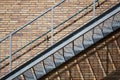 Exterior steel staircase on a red brick building wall with harsh shadow casting
