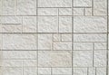 Exterior stone wall cladding made by white rock panels in tile shape of differen sizes.