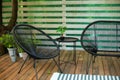 Exterior veranda of house with black Acapulco armchairs and plants pots. Cozy space in patio or balcony with chairs. Interior summ