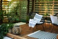 Exterior veranda of house with black Acapulco armchairs and plants pots. Cozy space in patio or balcony with garland. Interior Woo