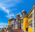 Exterior view of the Pena Palace with walls and yellow and red mosaics on the wall and fortified walls, under a sunny blue sky. Royalty Free Stock Photo