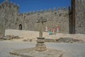 Exterior view of pillory with religious cross and the castle of Trancoso, medieval building with fortress wall, family of tourists